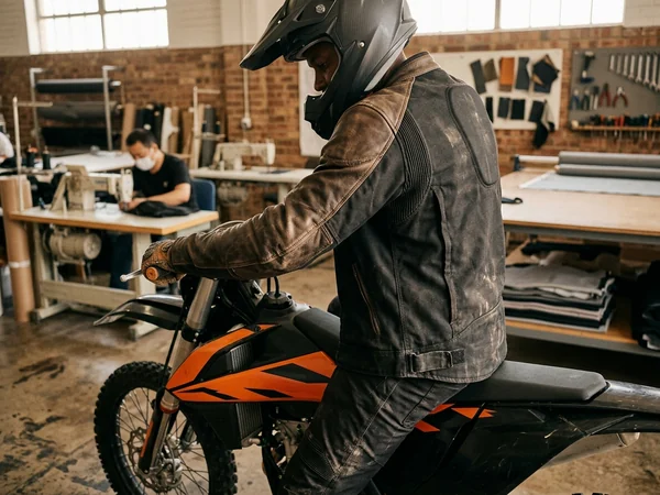 Rider on a bike in the sample jacket with armor in, reaching for the bars