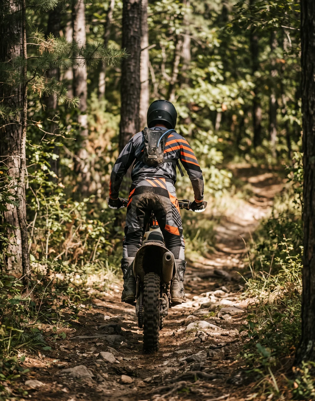 Custom enduro riding gear: rider standing on the pegs through forest singletrack in a sublimated jersey and 600D pants